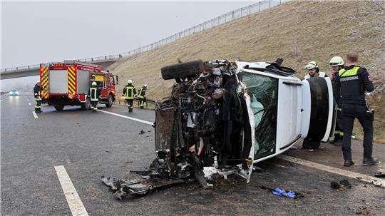 Ein beschädigtes Auto liegt auf der Seite. Im Hintergrund steht ein Rettungswagen.