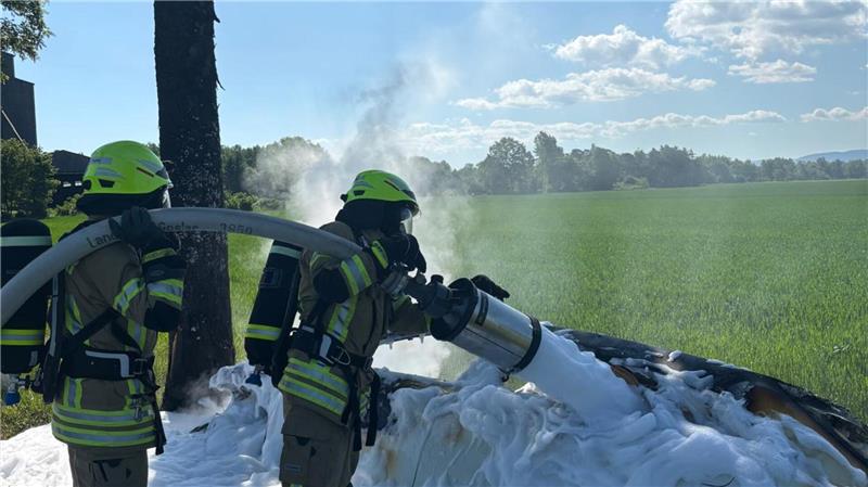 Feuerwehrmänner löschen das Feuer am Auto mit weißem Schaum