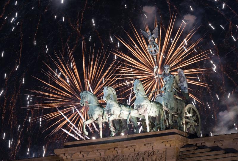 Das Feuerwerk zum Jahreswechsel steigt hinter dem Brandenburger Tor auf.