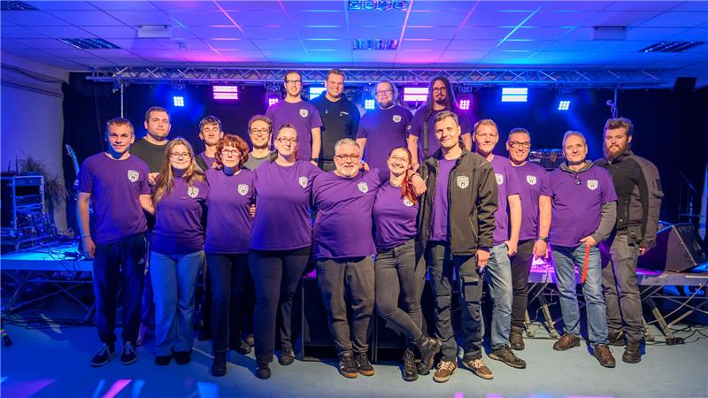 Gruppenbild mit Menschen in lila T-Shirts. 