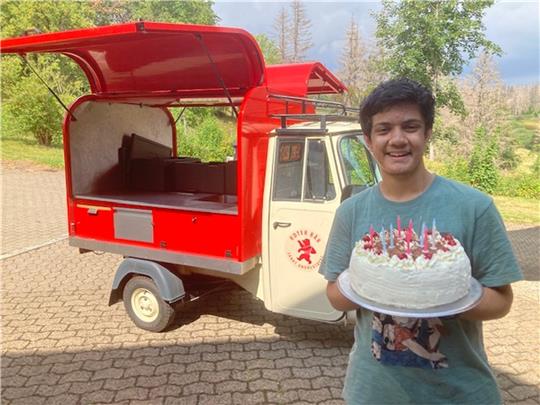 Das Gefährt im Hintergrund kennt Akshat Kapoor aus Indien auch aus seiner Heimat. Andreas Epting bringt die Schwarzwälder Torte stilecht per Ape.  Foto: Privat