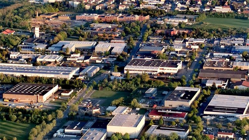 Luftaufnahme eines Gewerbegebiets mit mehreren großen Gebäuden, Straßen und Grünflächen
