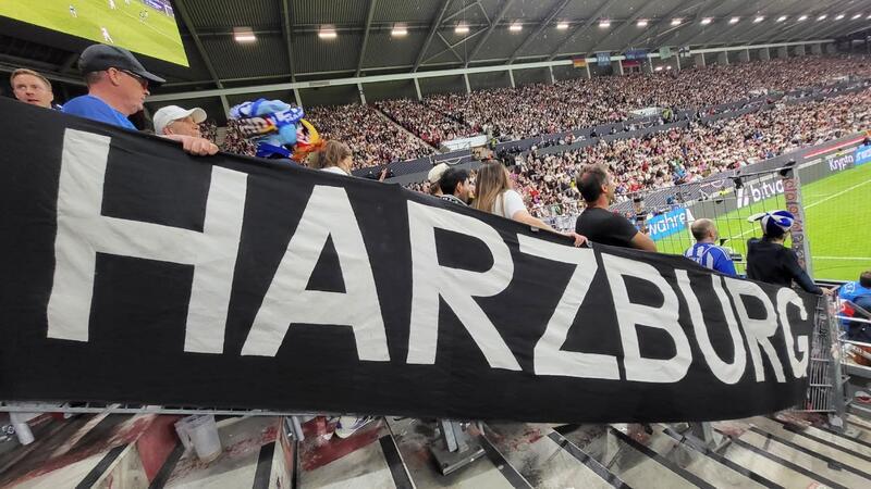 Ein riesiges Transparent mit der Aufschrift HARZBURG hängt in einem vollbesetzten Fußballstadion.