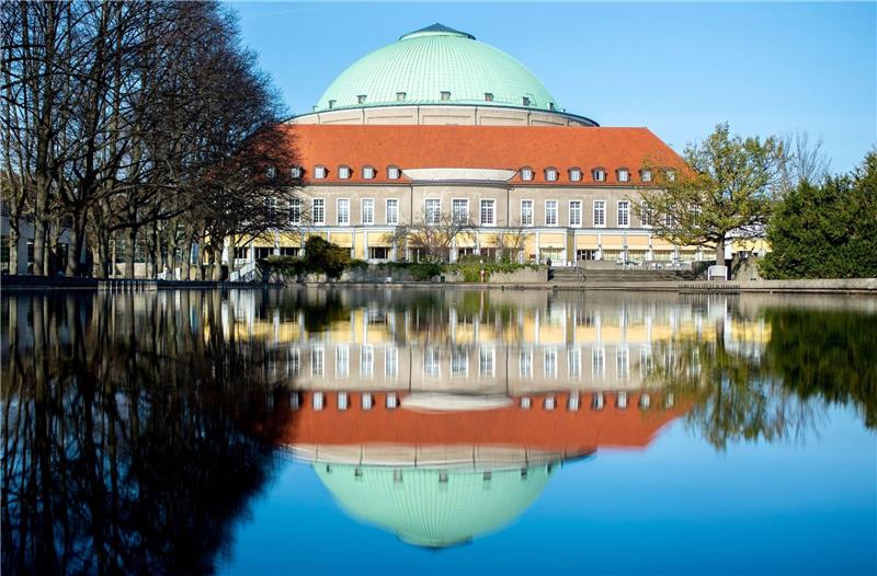 Das Hannover Congress Centrum (HCC) mit dem markanten Dach des historischen Kuppelsaals spiegelt sich in einem Teich im Stadtpark.