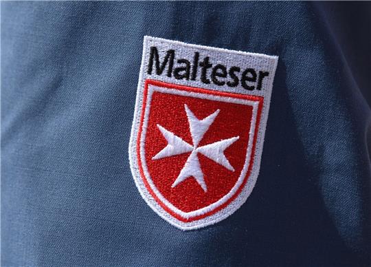Das Logo der Malteser ist an der Jacke eines Helfers zu sehen.