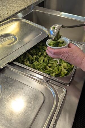 Oberharz: Was tut sich hinter den Kulissen einer Uni-Mensa? Hände, die Brokkoli in ein Schälchen füllen.