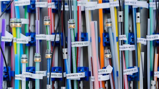 Mehrere bunte Kabel mit weißen Beschriftungsetiketten in einem Kabelmanagementsystem.