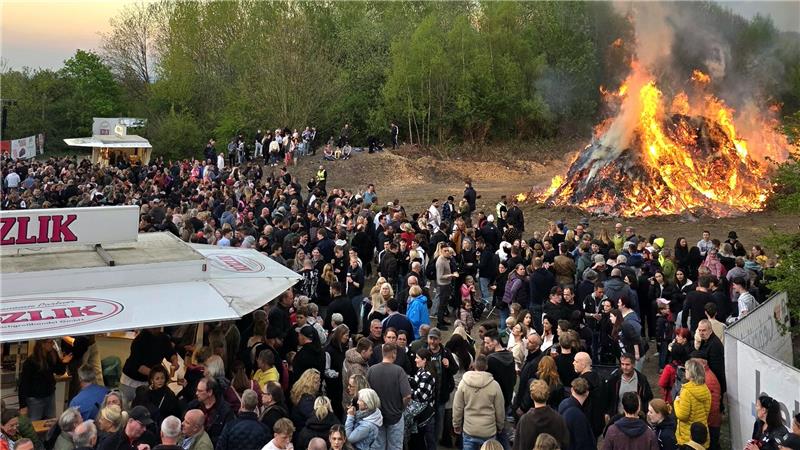 Vile Menschen schauen auf ein Osterfeuer, das licherloh brennt. 