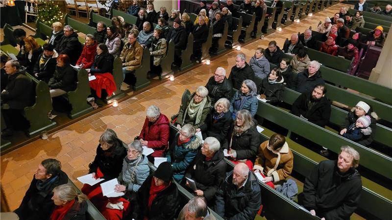 Kirchenbänke, auf denen Menschen sitzen und dem Konzert zuhören.