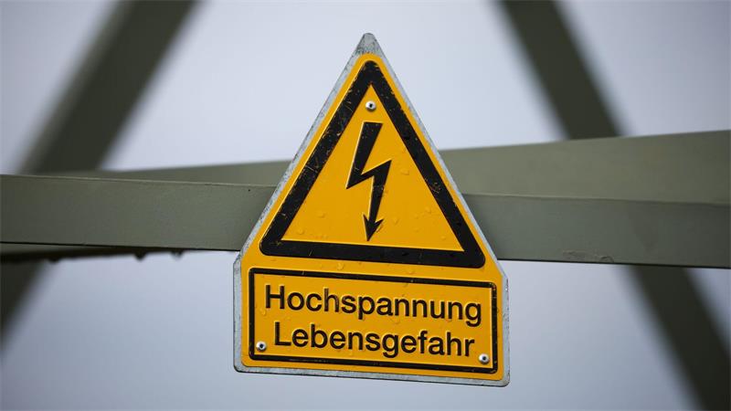 Ein Schild mit der Aufschrift "Hochspannung Lebensgefahr" hängt an einem Strommast.