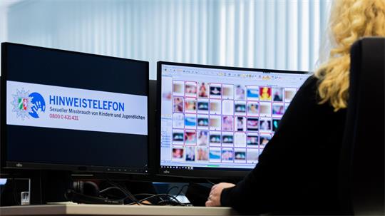Eine Ermittlerin sitzt im Landeskriminalamt am Hinweistelefon vor Monitoren mit unkenntlich gemachten Fotografien, die teilweise sexuellen Missbrauch zeigen.