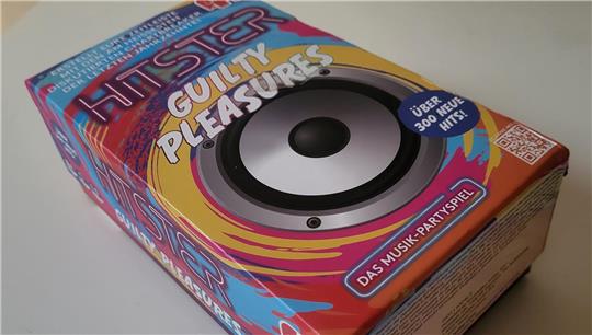 Bunte Verpackung eines Musik-Partyspiels mit großem Lautsprecherbild und Text 'HITSTER GUILTY PLEASURES'.
