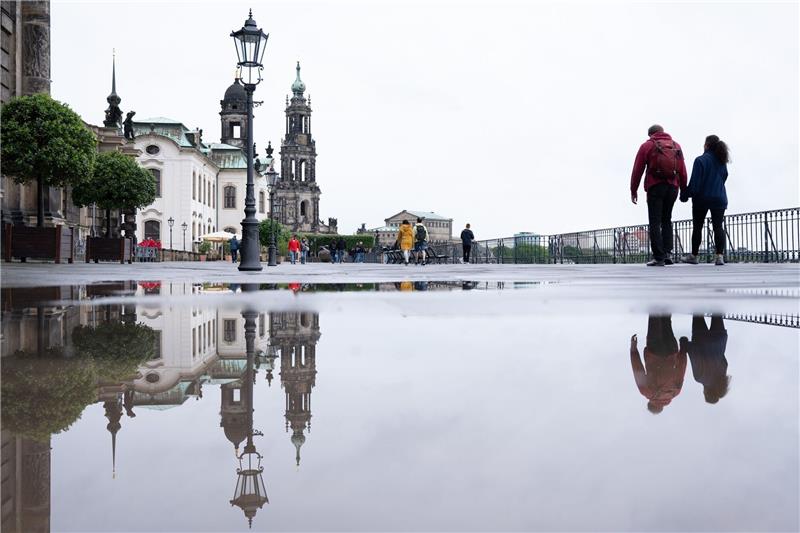Das Ständehaus (l-r), die Katholische Hofkirche und die Semperoper spiegeln  sich in einer Regenpfütze.