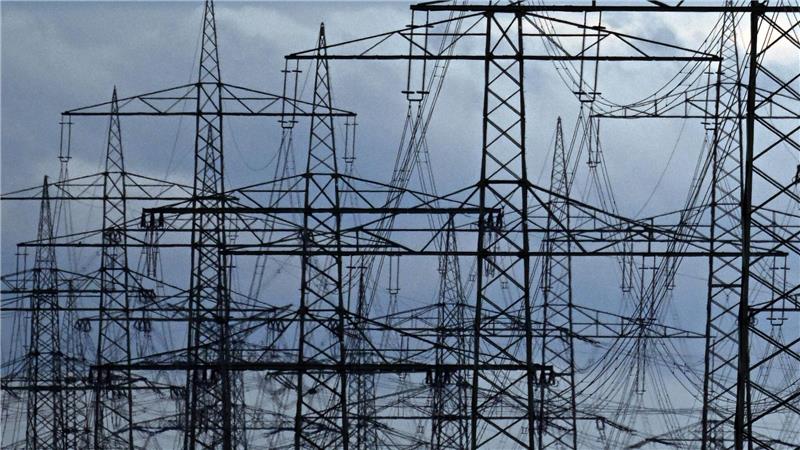 Das Foto zeigt Überland-Stromleitungen auf stählernen Strommasten, die dicht an dicht stehen. 