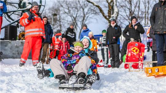 Zwei verkleidete Menschen rodeln mit einem Kunststoff-Bob.
