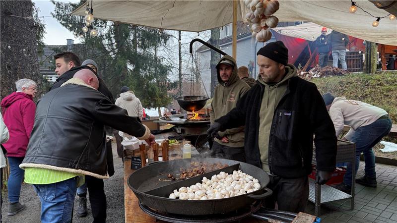 Ein Mann bereitet Champignons in einer großen Pfanne zu.