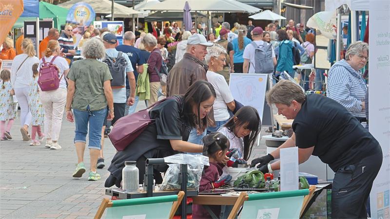 Ein bunter Markt mit Ständen und Schirmen und Menschen.
