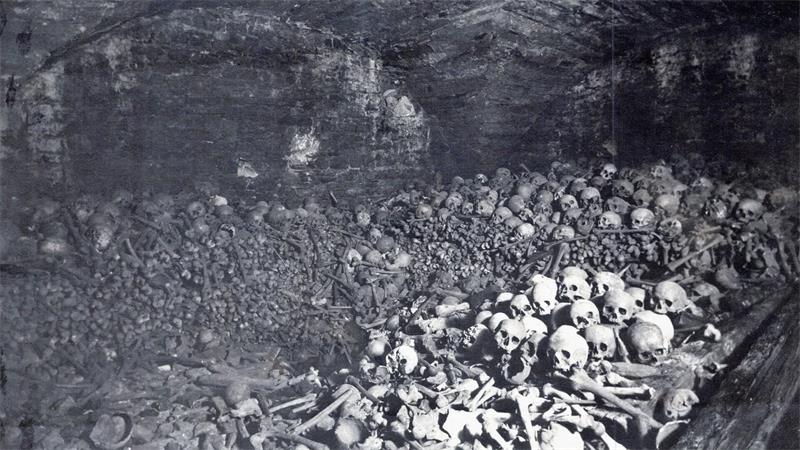 Große Ansammlung von Totenschädeln und menschlichen Knochen in einem gemauerten Gewölbe.