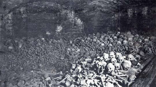 Große Ansammlung von Totenschädeln und menschlichen Knochen in einem gemauerten Gewölbe.