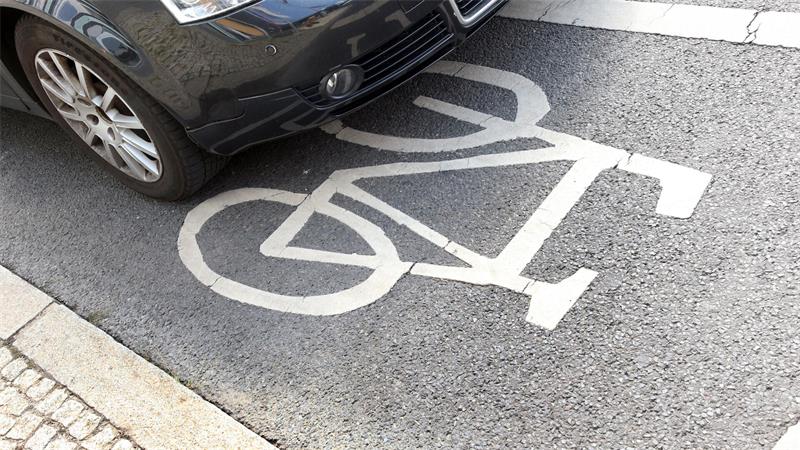 Vorderer Teil eines geparkten Autos steht auf einem Fahrrad-Piktogramm auf der Straße