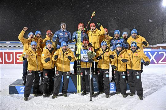 Das komplette deutsche Team feiert in Östersund Philipp Nawrath (M.). Dank des besten Rennens seiner Laufbahn sprintet der 30-Jährige nicht nur zum Triumph über zehn Kilometer, sondern erobert auch die Führung im Gesamtweltcup. Foto: Lundahl/dpa