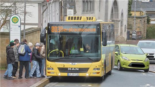 Gelber Linienbus der Linie 803 mit Zielanzeige 'Bergbaumuseum' an einer Haltestelle, an der mehrere wartende Personen stehen.