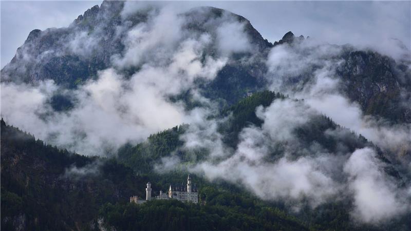 Bilder des Tages Das unter Regenwolken stehende Schloss Neuschwanstein wird von der Sonne beschienen.