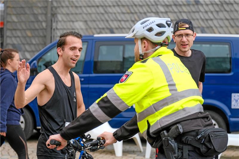 Dean Sauthoff, Sieger in beiden Rennen bei den Männern, klatscht einen Kollegen ab. Die Polizei eskortiert die Läufer auf Fahrrädern ins Ziel. Hinten Florian Nolte.