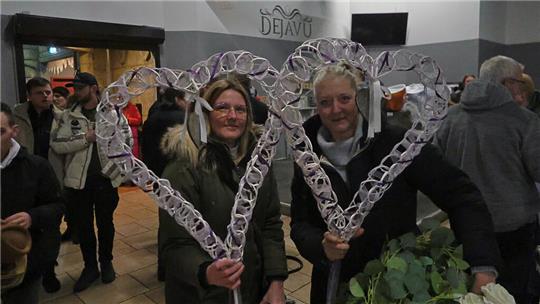 Zwei Frauen halten jeweils ein geflochtenes Herz in der Hand.