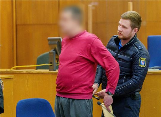 Dem Angeklagten (l) werden die Handschellen abgenommen.