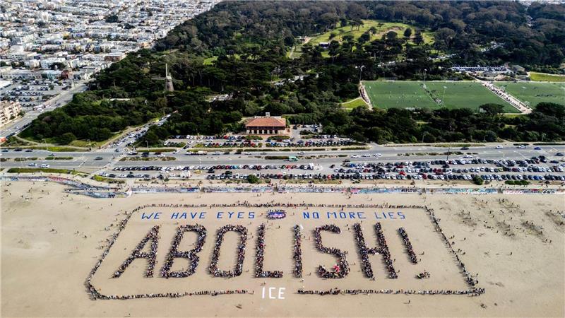 Demonstranten bilden ein menschliches Banner „We have eyes - no more lies - Abolish“ am Ocean Beach in San Francisco während eines Protests gegen die US-Einwanderungsbehörde ICE.