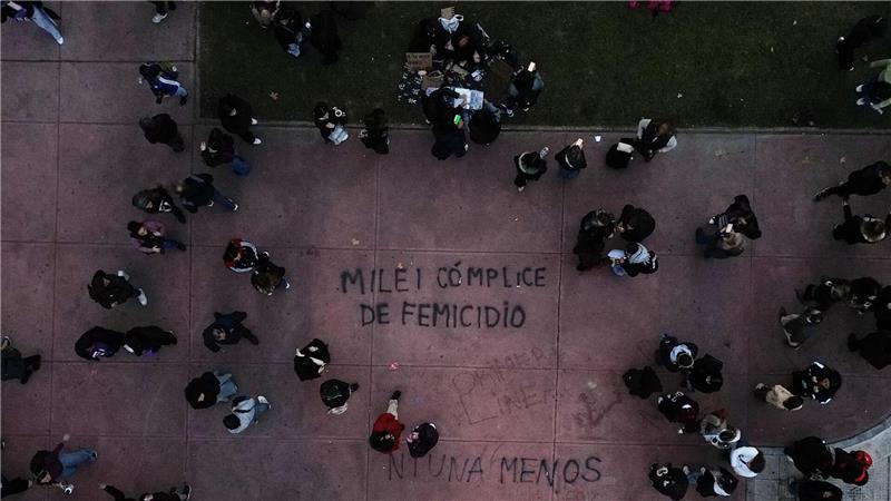 Demonstranten gehen in Buenos Aires in der Nähe eines Schriftzugs „Milei femicide accomplice“ (Milei Frauenmord Mittäter), der sich auf Präsident Javier Milei bezieht, während eines Marsches zum Jahrestag der Frauenbewegung „Ni Una Menos“ (Nicht eine weniger).