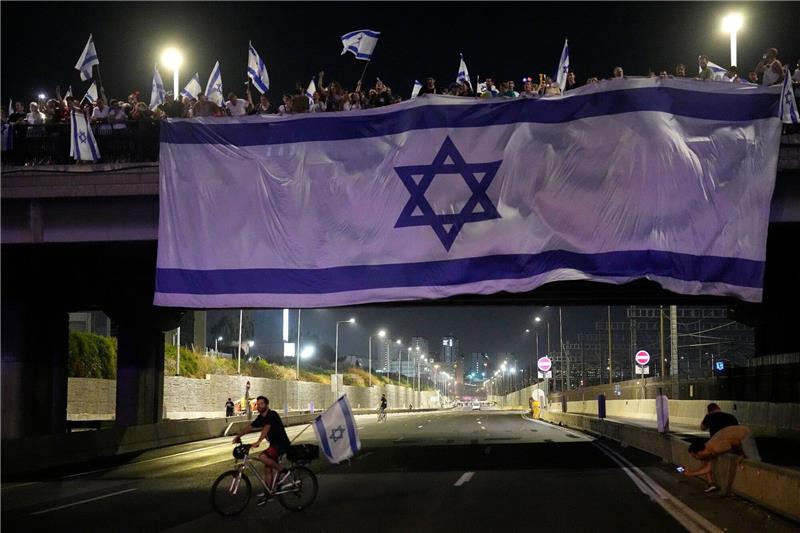 Demonstranten haben bei ihren Protesten eine riesige Nationalfahne an einer Autobahnüberführung in Tel Aviv aufgehängt.