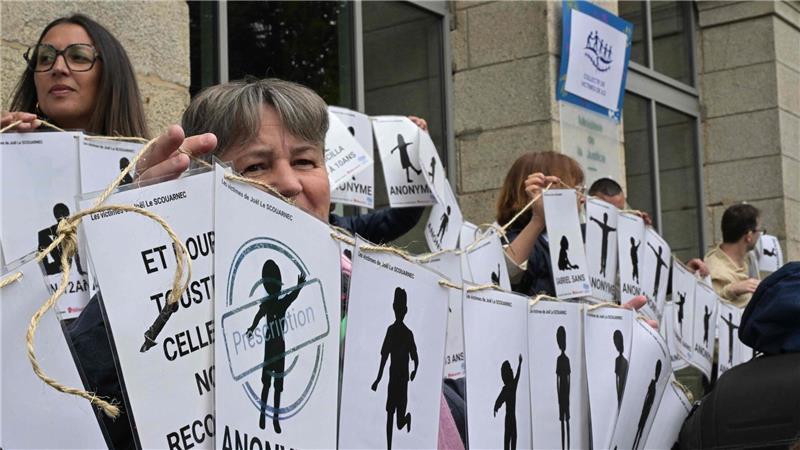 299-facher Missbrauch: 20 Jahre Haft für Arzt in Frankreich Demonstranten halten vor dem Gerichtsgebäude Schilder mit den Namen der Opfer.