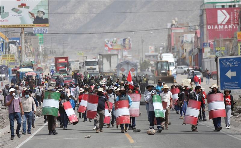 Demonstranten marschieren bei einem Protest gegen die Regierung von Präsidentin Boluarte mit behelfsmäßigen Schildern über eine Straße im peruanischen Arequipa.