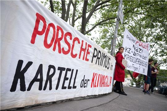 Demonstranten mit Plakaten vor Beginn der Porsche-Hauptversammlung in Stuttgart.
