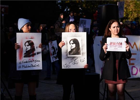 Demonstrantinnen halten in Berlin Schilder in die Höhe, auf der die im Iran getötete Kurdin Jina Mahsa Amini zu sehen ist.