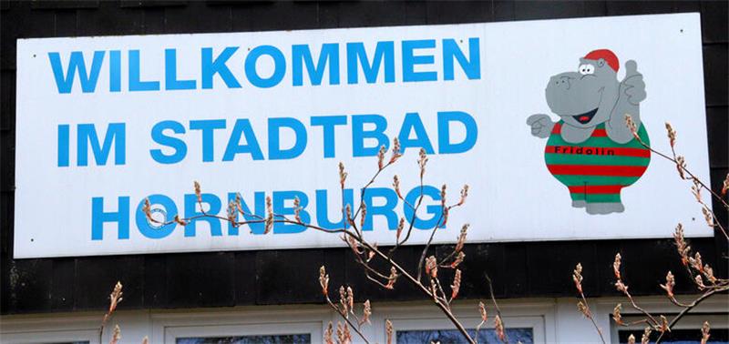 Schild mit der Aufschrift "Willkommen im Stadtbad Hornburg" und einem Nilpferd in rot-grünem Badeanzug, dem Logo des Stadtbads.