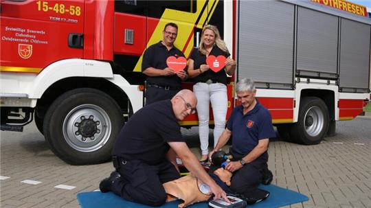 Dennis Dorn und Anke Behrens freuen sich. Die Feuerwehrkameraden Heiko Wolff (li.) und Lutz Appelt demonstrieren die Anwendung.
