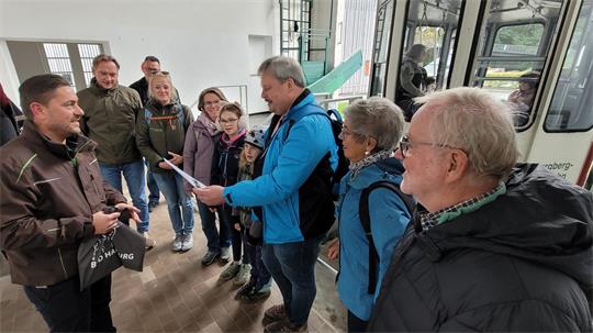 Dennis Kasischke übergibt Andreas Jeromin und seiner Familie eine Urkunde, die die Besonderheit ihrer Seilbahn-Fahrt belegt. Darüber hinaus gibt es Gutscheine.