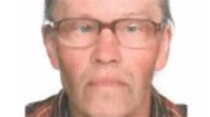 Ein betagter Mann mit Brille, Toupet und bräunlich-karriertem Hemd.