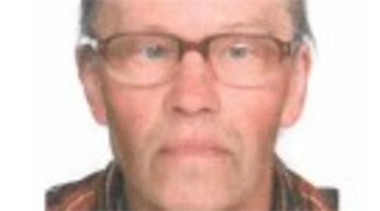 Ein betagter Mann mit Brille, Toupet und bräunlich-karriertem Hemd.