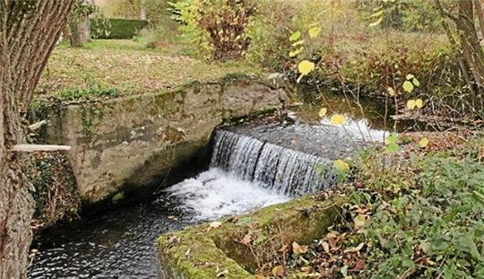 Wasser stürzt einen kleinen Absturz im Flussbett hinunter.