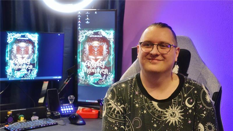 Jan Beyer alias "Gipfelbasilisk" in seinem Büro, in die Kamera lächelnd.