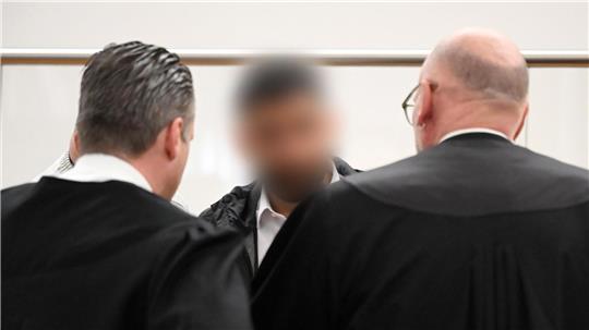 Der Angeklagte (M) spricht im Gerichtssaal mit zwei Strafverteidigern. Zu Prozessbeginn sind weiterhin viele Fragen offen.