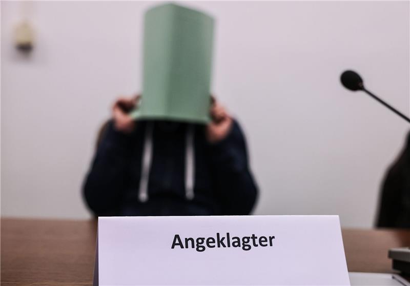 Der Angeklagte im Missbrauchskomplex Wermelskirchen hält sich im Gerichtssaal eine Mappe vor das Gesicht.