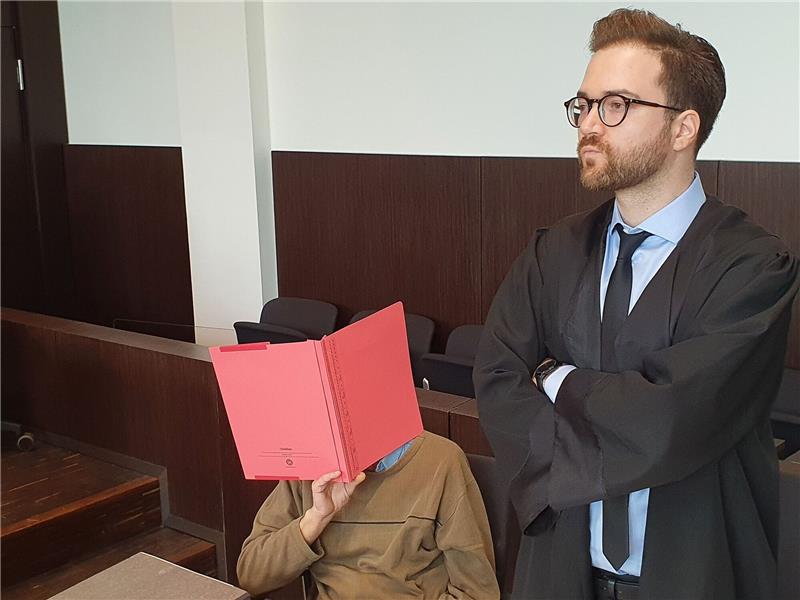„Cold Case” - Prozess um „Mord im Maisfeld” gestartet Der Angeklagte (l) sitzt neben seinem Verteidiger Maximilian Klefenz im Verhandlungssaal des Düsseldorfer Landgerichts und verdeckt sein Gesicht.