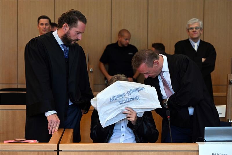 Der Angeklagte (m.) vor Beginn des Prozesses im Gerichtssaal in Aachen.