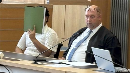 Der Angeklagte mit seinem Verteidiger: Der 24-Jährige versteckt sein Gesicht hinter einer Mappe.