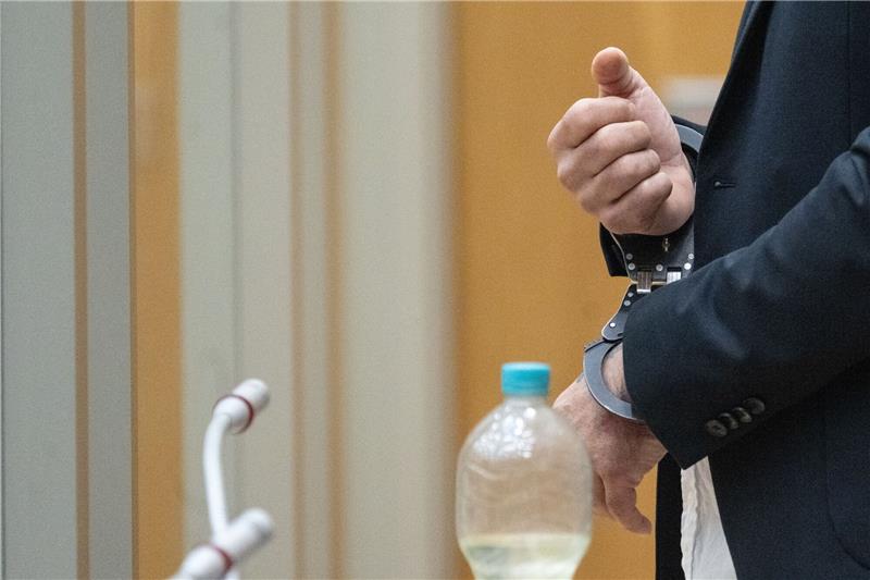 Lange Haftstrafe für Angeklagten in „Reichsbürger”-Prozess Der Angeklagte steht in Handschellen in einem Saal des Oberlandesgerichts Stuttgart.